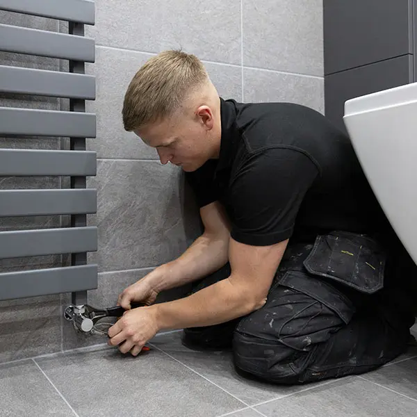 a plumber fixing a radiator that has cold spots