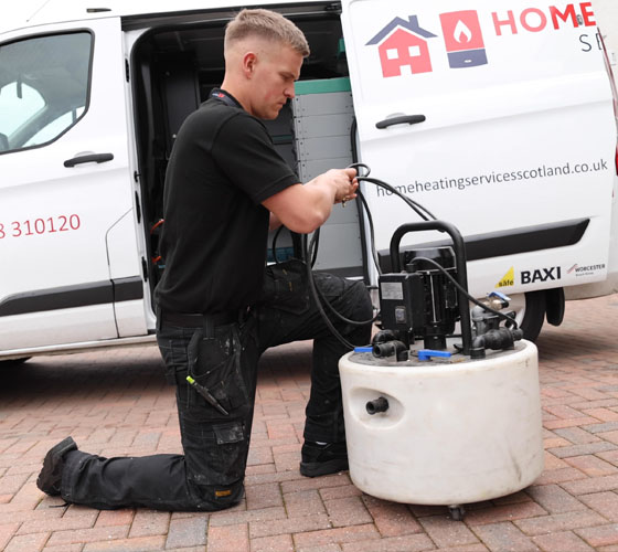A plumber carefully installing a power flush system